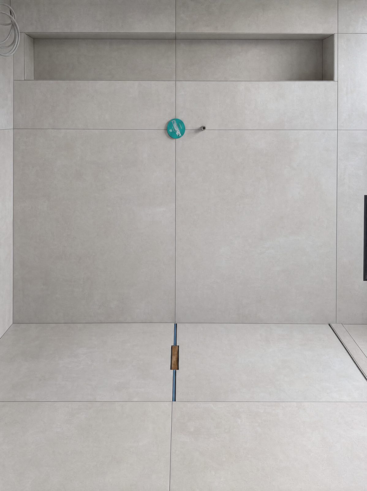 Bodengleiche Dusche mit großformatigen Wand- und Bodenplatten in Grau, Wandnische und Duschrinne